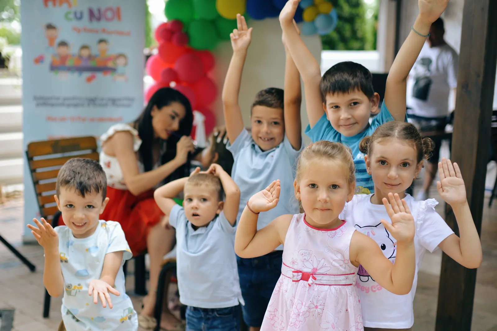 Copii bucuroși, cu mâinile ridicate, la o petrecere Hai cu noi la joacă