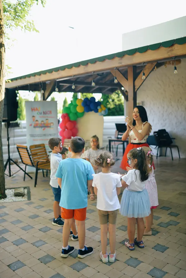 Copii jucându-se în cerc sub foișor